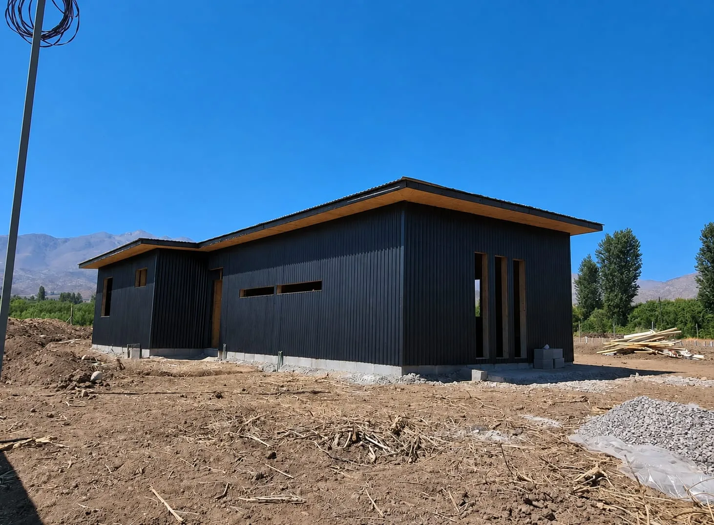 Casa en construcción con aleros de madera y revestimiento metálico